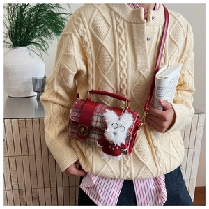Détail du sac bandoulière à carreaux rouges avec sangle en cuir et breloque chiot blanc