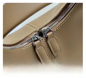 Detail of silver dual zippers with khaki leather pulls and precise white stitching