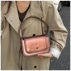 Close-up of metallic bronze small square bag with round rivet closure and twin handles