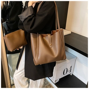 Sac fourre-tout marron en similicuir avec petite pochette zippée porté par un mannequin