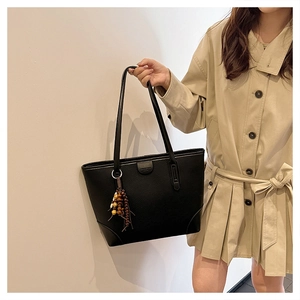 Close-up of black pebble leather tote bag with stylish colorful wooden bead tassel charm
