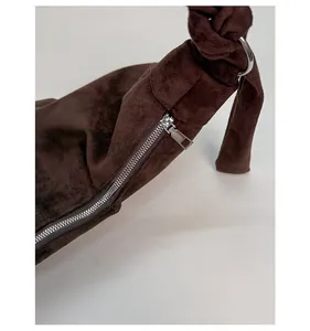 Detail of dark brown suede shoulder bag with silver metal zipper and knotted handle strap
