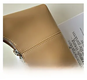 Close-up of precise double stitching and silver metal zipper on brown leather handbag