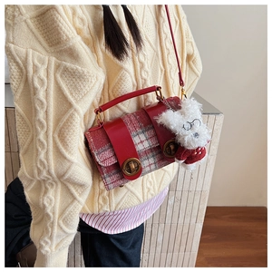 Détail du sac bandoulière en tweed rouge avec pendentif chiot en peluche et anneaux en métal