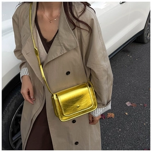 Close-up of metallic gold crossbody bag with glossy texture on a fashion model