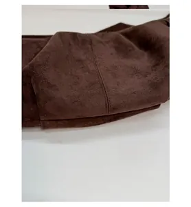 Detailed macro view of straight stitching on premium brown suede leather shoulder bag