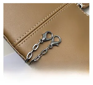 Detail shot of brown lychee grain leather handbag with silver metal chain and lobster clasp