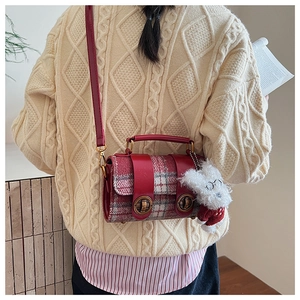 Détail du mini sac à main à carreaux rouges avec boucles et breloque peluche chien