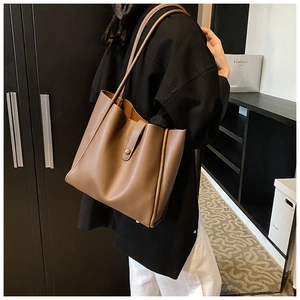 Sac fourre-tout marron en similicuir porté par un mannequin dans un décor élégant