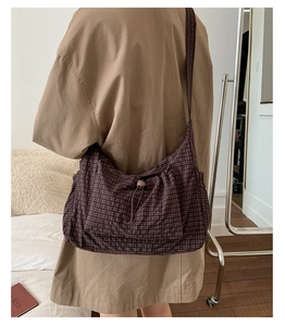 Détail du sac bandoulière en toile à carreaux avec fermeture à cordon et poche externe