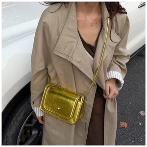 Detail of metallic gold crossbody bag showing its glossy mirror finish and fine texture