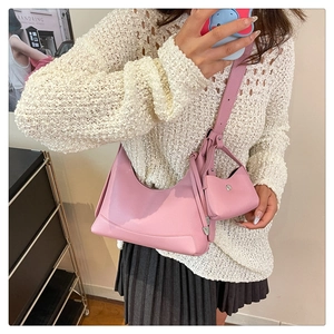 Rosafarbene Hobo-Tasche aus Leder mit Litschistruktur und Anhänger an einem Modell
