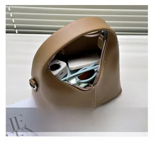 Detail view of the interior capacity showing a camera and sunglasses in the soft leather bag
