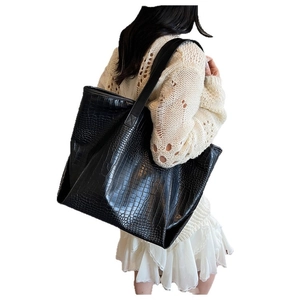 Chic black crocodile embossed tote bag worn by a model for a casual commute style