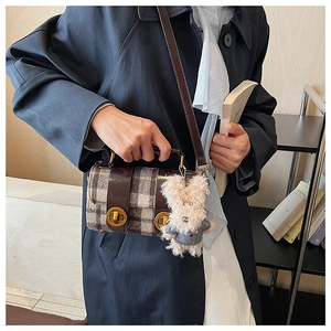Détail du sac bandoulière en laine à carreaux avec finitions cuir et breloque chien