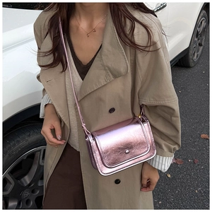 Detail of lavender metallic crossbody bag with silver round buckle and grainy texture