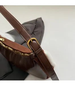 Détail du sac en cuir marron avec boucle dorée et bordure en fourrure blanche