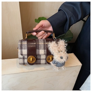 Vue détaillée d'un sac à carreaux vintage avec garniture en cuir et charme peluche