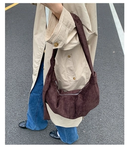 Close-up of a brown suede crescent bag featuring a knotted strap detail and metal zipper