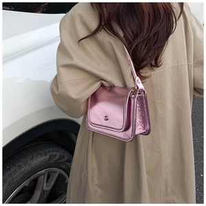 Detail of pink metallic crossbody bag with flap cover shown on a casual trench coat outfit