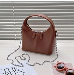Detail view of caramel brown leather handbag with silver chain strap and trapezoid structure