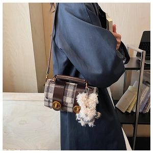 Détail du sac bandoulière vintage à carreaux avec garniture en cuir et breloque ours