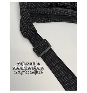 Détail d'une bandoulière réglable à carreaux noir et blanc avec boucle en plastique