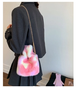 Detailed view of pink and white plush bucket bag with golden chain strap on shoulder