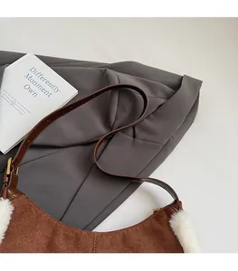 Détail d'un sac bandoulière en daim marron avec bordure en peluche blanche et boucles