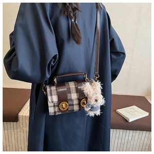 Détail du sac bandoulière à carreaux avec fermoirs dorés et breloque chiot en peluche