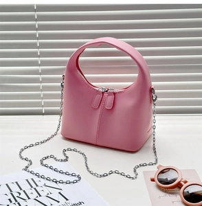 Detail of pink half-moon handbag featuring silver chain strap and smooth matte leather