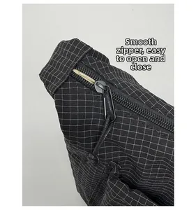 Détail de la fermeture éclair fluide avec cordon sur le sac bandoulière noir en nylon