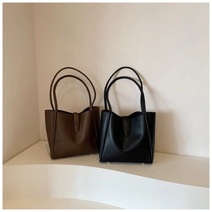 Vue détaillée de grands sacs cabas en marron foncé et noir avec texture cuir et boucle