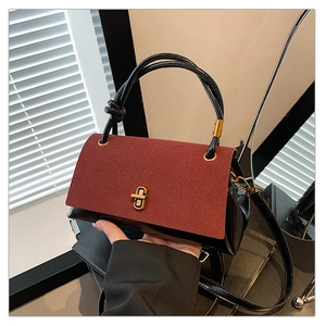Detail of vintage crossbody bag with burgundy suede flap and gold twist lock