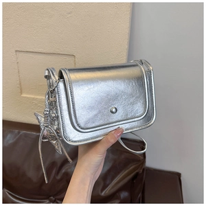 Detail of silver metallic crossbody bag with magnetic snap and star pendant charm