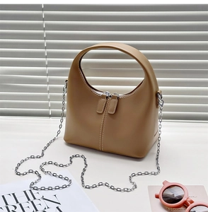 Detail of khaki leather semi-circle handbag with silver chain and dual zipper on white table