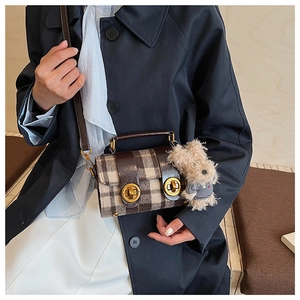 Détail du sac bandoulière vintage à carreaux avec fermoirs dorés et charme peluche