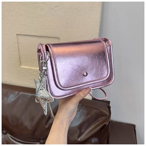 Detailed macro view of metallic pink crossbody bag with a shiny silver star pendant charm