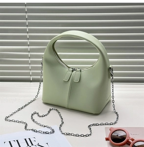 Detail of light green trapezoid bag with smooth leather finish and silver chain strap