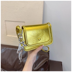 Detail of metallic gold mini crossbody bag featuring a silver balloon dog charm decoration