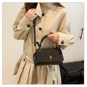 Detail of black leather square handbag featuring gold twist-lock and detachable strap