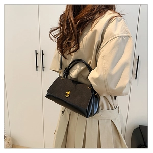 Detailed close-up of a black textured crossbody bag with gold clasp shown on a model