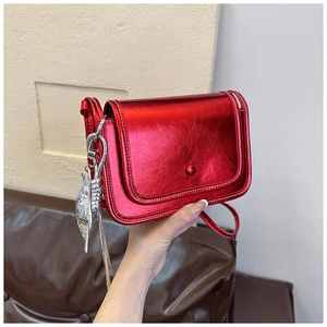Detail of metallic red crossbody bag with white stitching and silver fish charm