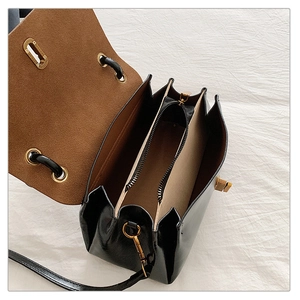 Detail view of black faux leather bag interior with brown suede lining and triple gusset