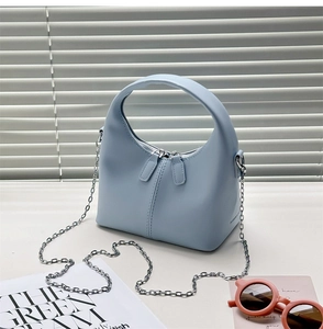 Close-up of light blue PU leather bag with double zippers and silver chain strap