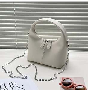Detailed view of white half-moon leather handbag with dual zippers and silver chain strap