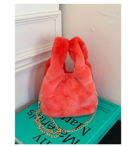 Close-up of bright orange plush handbag with soft faux fur texture and gold chain strap