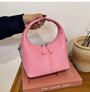Detail of pink semi-circular handbag with smooth leather texture and silver chain strap
