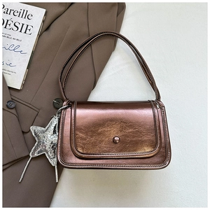 Detail of metallic bronze crossbody bag with glossy textured leather and star charm