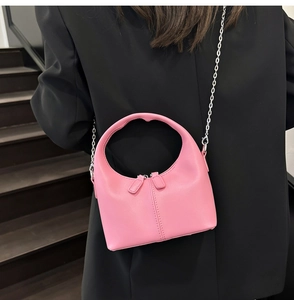 Detail of pink crescent bag with dual zippers and silver chain on black blazer